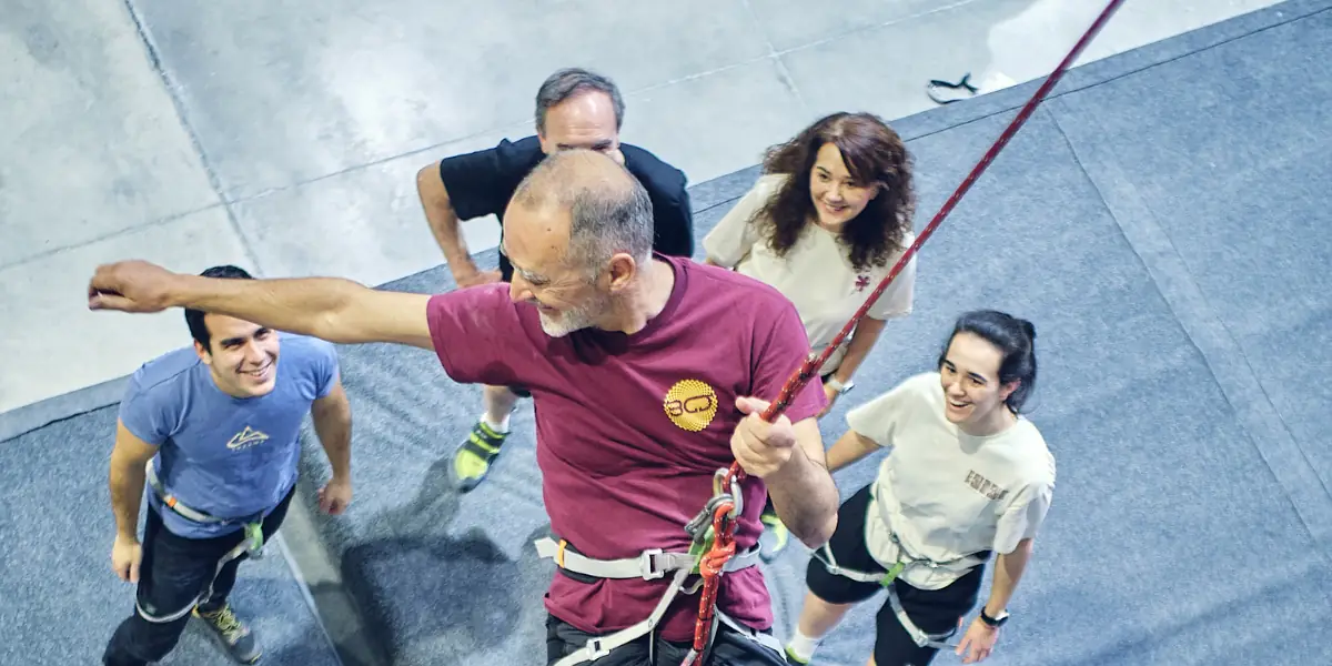 Team building activities for companies in Madrid with a participant climbing while the team supports them