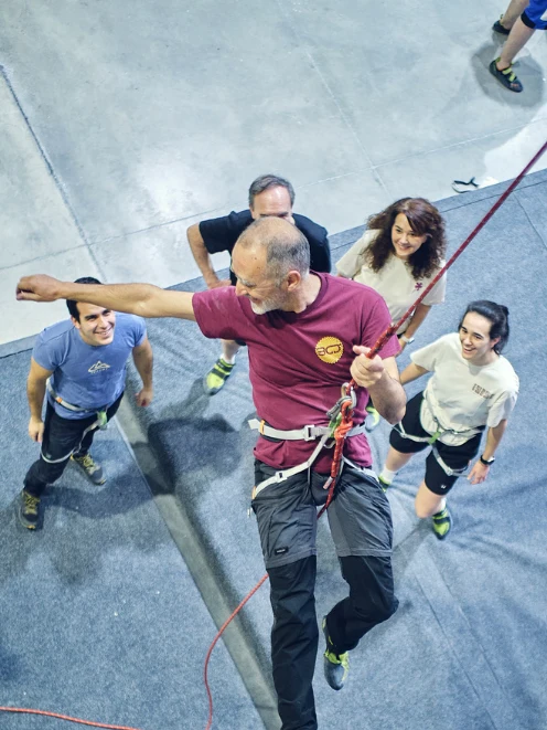 ideas de team building para grupos Madrid hombre escalando mientras el equipo acompaña ideas de team building para grupos Madrid hombre escalando mientras el equipo acompaña