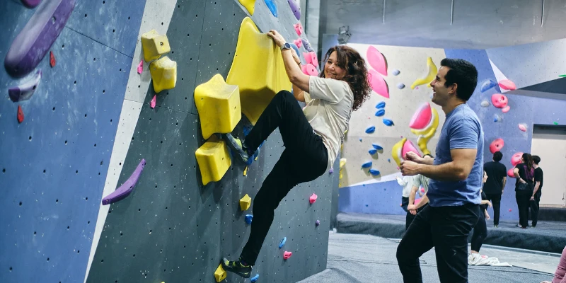 team building en Madrid mujer escalando acompañada de instructor